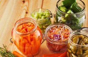 Potes de vidro com legumes fermentados em processo de conservação